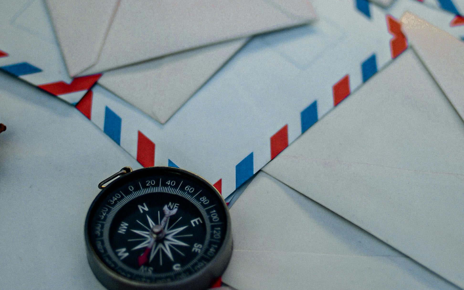 Compass on a stack of assorted letters.